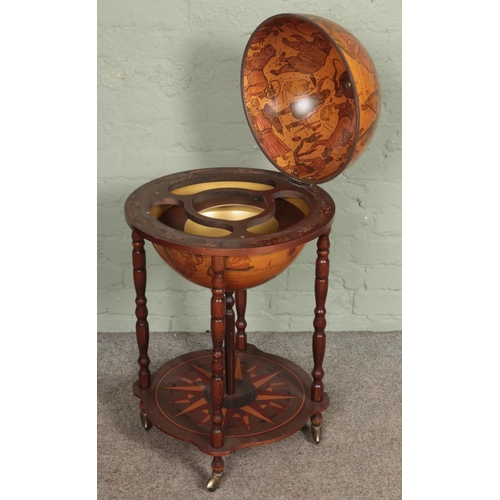 602 - A Globe drinks cabinet, with turned oak supports, hinged top, horoscopic border and rotating base. R... 