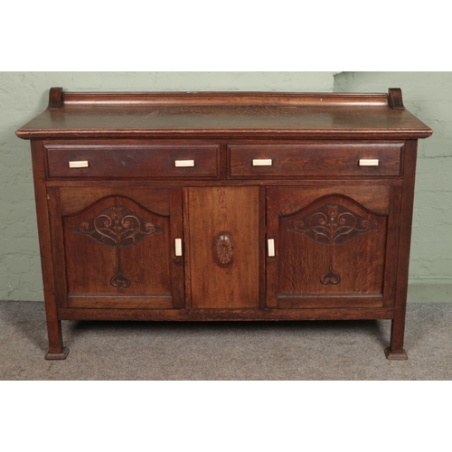 603 - A carved oak sideboard with bakelite handles. (103cm x 153cm x 57cm)