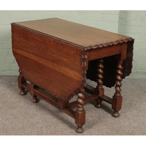 610 - A carved oak barley twist gateleg drop leaf dining table with scalloped edge. (73cm x 106cm x 54cm)