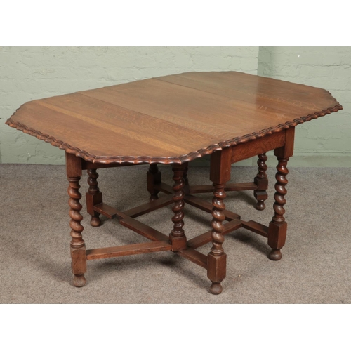 610 - A carved oak barley twist gateleg drop leaf dining table with scalloped edge. (73cm x 106cm x 54cm)