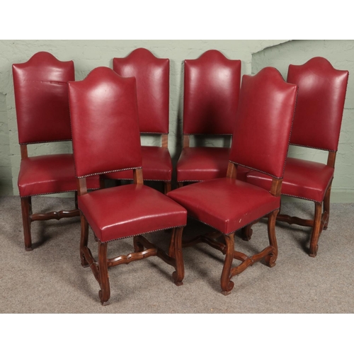 615 - A set of six studded red leather dining chairs with scrolled supports.