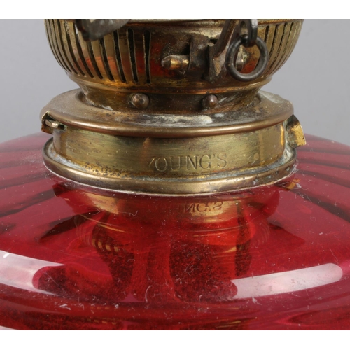 167 - A Victorian Young's cranberry glass and brass oil lamp. (63cm)