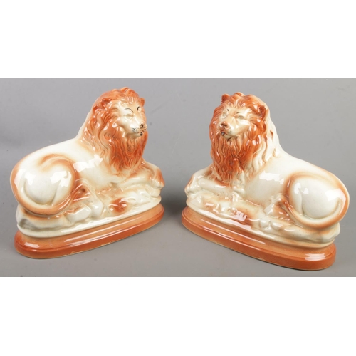 173 - A pair of pottery mantel lions in recumbent pose.