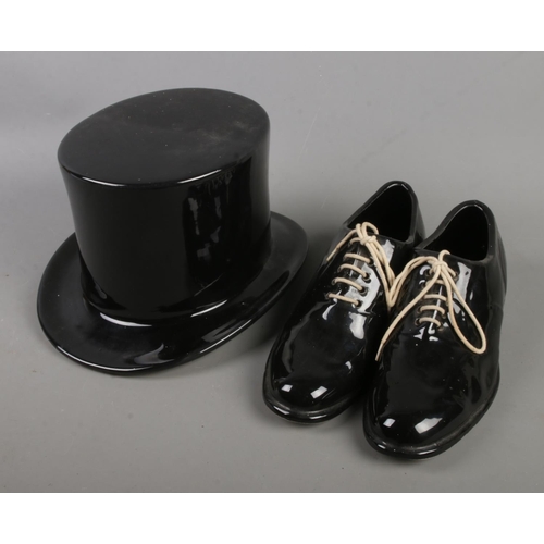 179 - A ceramic top hat along with a pair of ceramic dress shoes decorated with white laces.