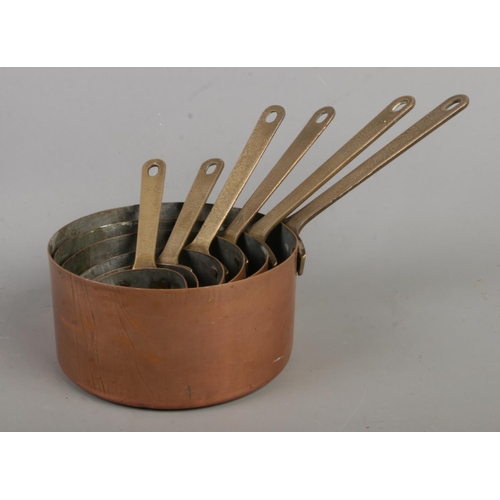 183 - Two sets of six graduated copper pans, with brass handles.