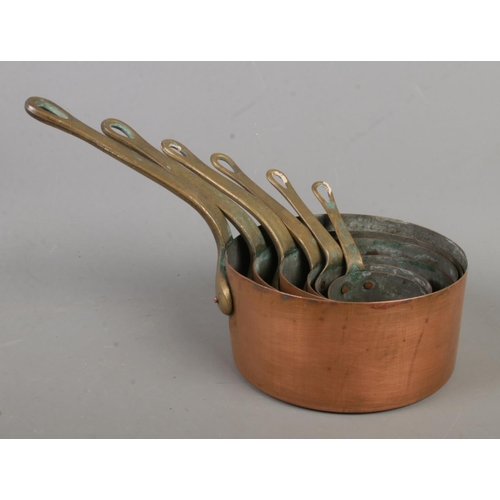 183 - Two sets of six graduated copper pans, with brass handles.