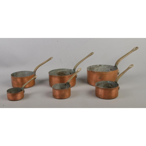 183 - Two sets of six graduated copper pans, with brass handles.