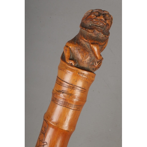 202 - A Chinese bamboo walking stick with carved pommel of a foo dog and wise men carved along shaft.