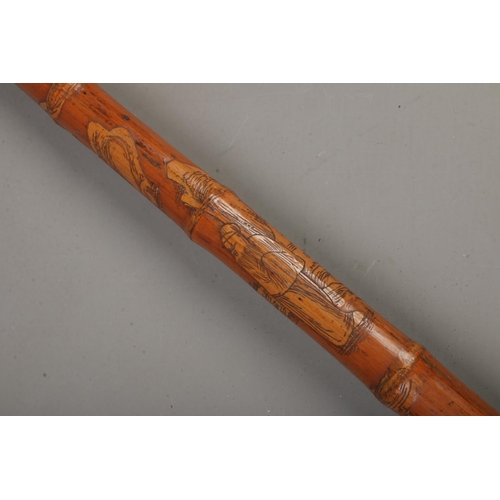 202 - A Chinese bamboo walking stick with carved pommel of a foo dog and wise men carved along shaft.