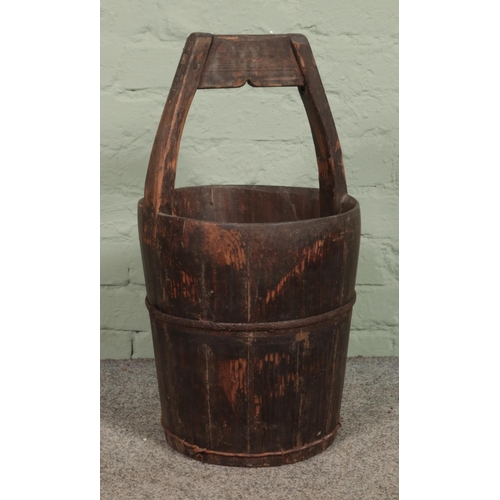 335 - An antique wooden well bucket, with metal mounts. 62cm tall.