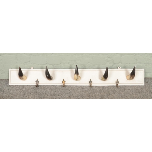 347 - A wooden wall mounting coat rack with cattle horns. Length 110cm.