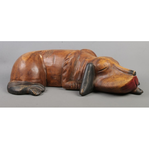 359 - A large carved wooden figure of a sleeping dog. Length: 60cm.