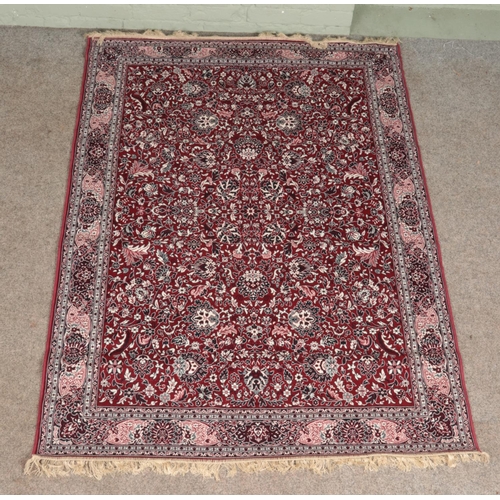 363 - A red ground wool rug, with all over floral decoration and frilled edge. Length: 203cm, Width: 140cm... 