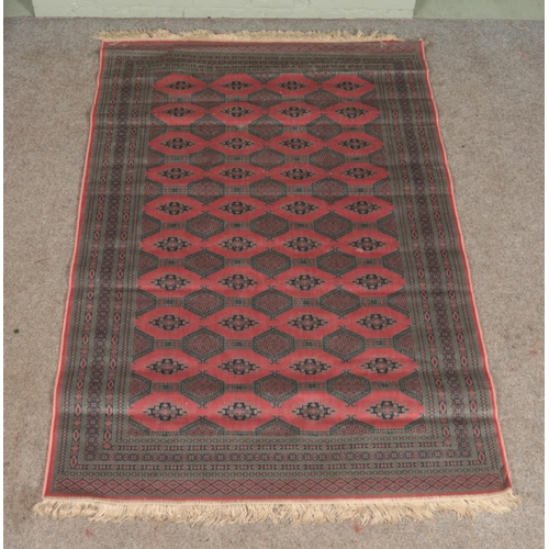 364 - A pink ground Bokhara rug, with blue patterned border and frilled edge. Length: 212cm, Width: 139cm.