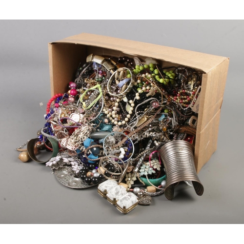82 - A large box of costume jewellery including large bangles and necklaces.