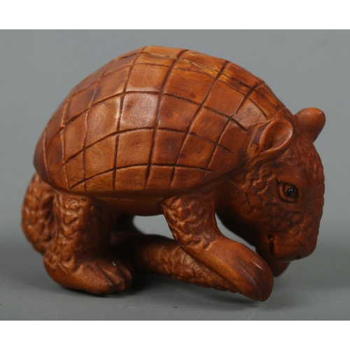 520 - A hand carved hardwood netsuke of a pangolin, signed to base.