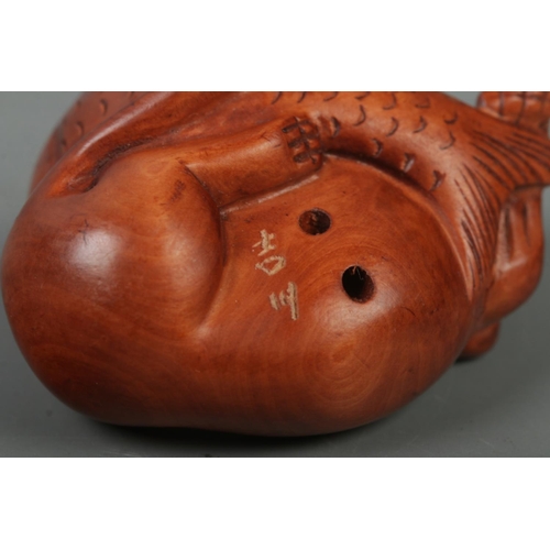 522 - A hand carved hardwood netsuke of a cat with fish, signed to base.