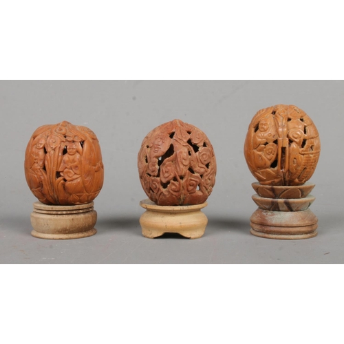 530 - Three carved coquilla nut figures on plinths featuring carved outer shell cover.