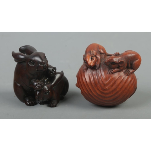 539 - Two carved hardwood netsukes, depicting two rabbits and three mice within a nutshell. Both signed.