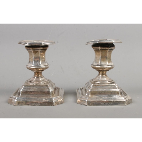 548 - A pair of early twentieth century weighted silver dwarf candlesticks, with octagonal tops, on square... 