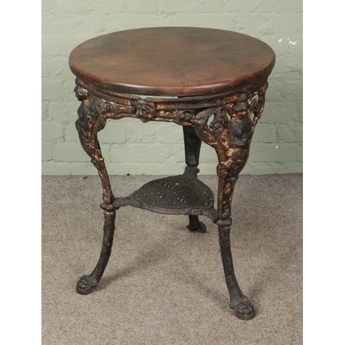 608 - A cast iron based pub table featuring Britannia and lion mask design with wooden circular top. Appro... 