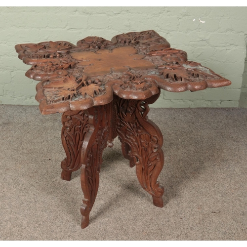 614 - An extensively carved mahogany occasional table with folding base. Height 63cm, Top dimensions 63cm ... 