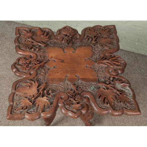 614 - An extensively carved mahogany occasional table with folding base. Height 63cm, Top dimensions 63cm ... 