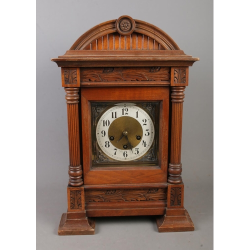 149 - An oak cased mantle clock featuring J Unghans movement and carved foliage motifs. With key.