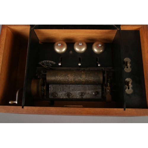 161 - An antique music box featuring three bells housed in oak case.