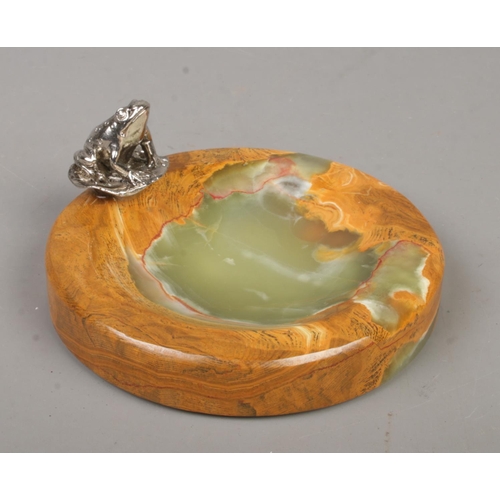 229 - A polished onyx trinket dish surmounted with a white metal figure of a frog. Diameter of dish 12cm.