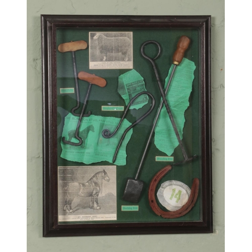 477 - A framed display of various farming tools including Boot pulls, shepherd's crook, branding iron, doc... 