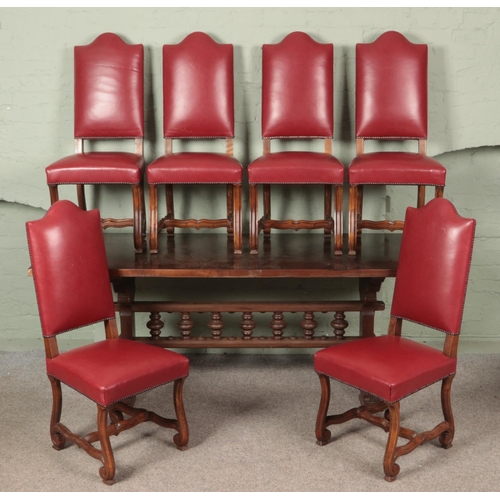 638 - A large oak dining table with spindle stretcher along with six studded red leather dining chairs. (2... 