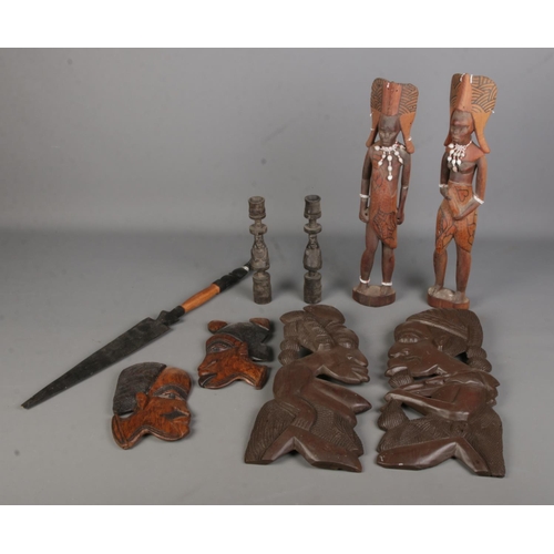 128 - A collection of tribal woodenwares, to include face wall plaques, candlesticks and figures.