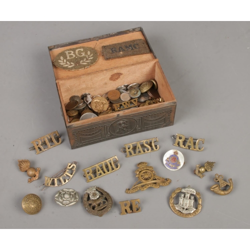 218 - A small box containing mainly cap badges pins and lapels, together with a small collection of coins.... 