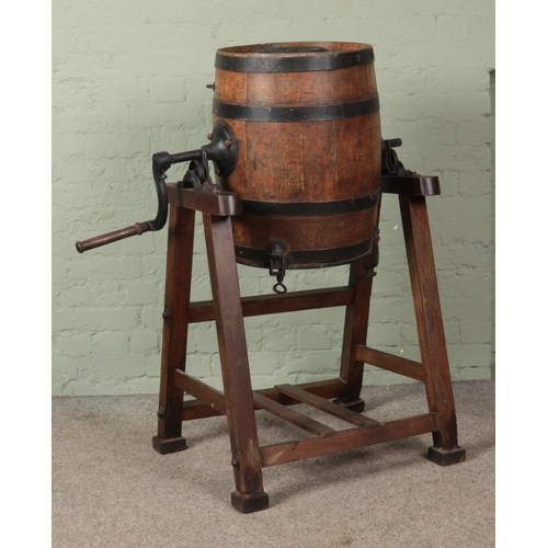 386 - An oak and metal bound barrel formed as a butter churn, raised on pine stand. The barrel stamped and... 