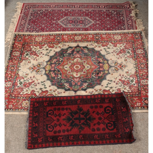 405 - Three rugs. Includes red ground wool runner with central medallion motif, etc.