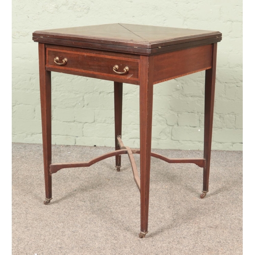 588 - An Edwardian mahogany envelope card table, with drawer to the front, baize interior and banded decor... 