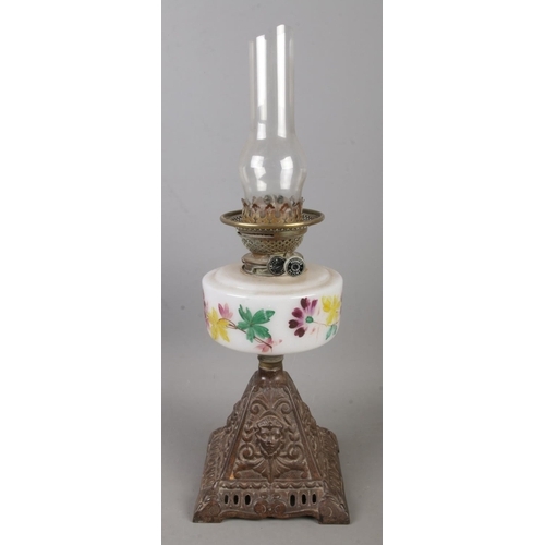 160 - A Youngs brass oil lamp with painted glass reservoir decorated with leaves and flowers.