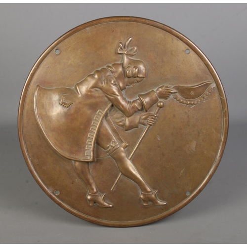 112 - A large circular bronze plaque, depicting a gentleman holding a cane doffing his hat. Diameter: 41cm... 