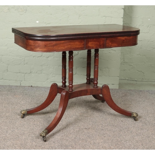 560 - A Victorian mahogany fold over table. Raised on brass lion paw castors.