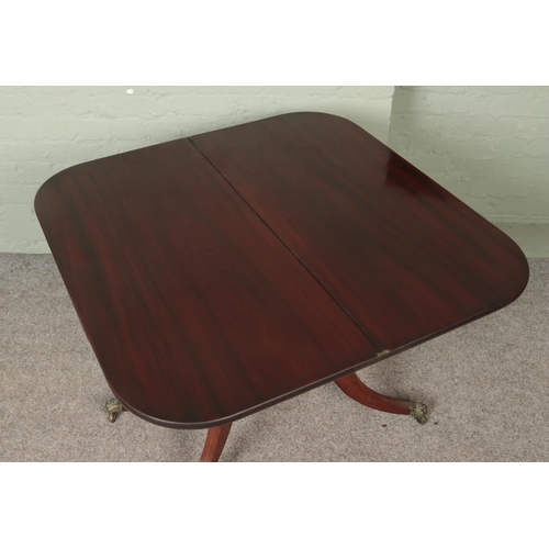 560 - A Victorian mahogany fold over table. Raised on brass lion paw castors.