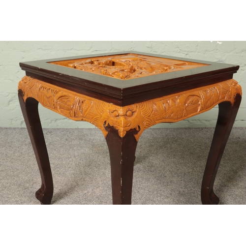 564 - A pair of Oriental hardwood occasional tables. Having deep carved decoration to tops depicting figur... 