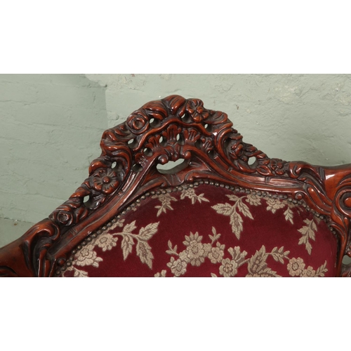 578 - A pair of carved mahogany tub arm chairs with red floral upholstery.