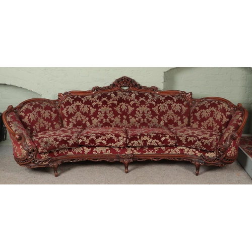 579 - A very large carved mahogany sofa with red floral upholstery. Length 280cm.