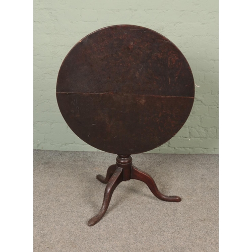 591 - An oak tilt top table on three cabriole legs. Approx. table diameter 75cm.