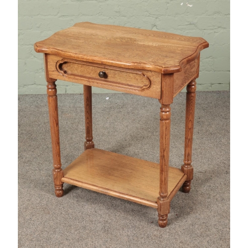 593 - A light oak two side side table featuring singular drawer. Approx. dimensions 61cm x 39cm x 68cm.