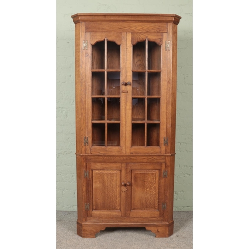 594 - An oak glazed front corner cupboard by M.K Griffin. Approx. dimensions 88cm x 41cm x 188cm.