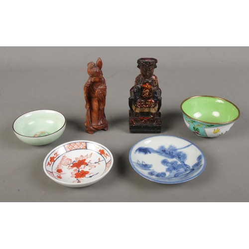 132 - A collection of oriental wares including a wooden carved figure of a emperor, enamelled dish, celado... 