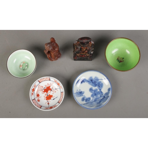 132 - A collection of oriental wares including a wooden carved figure of a emperor, enamelled dish, celado... 