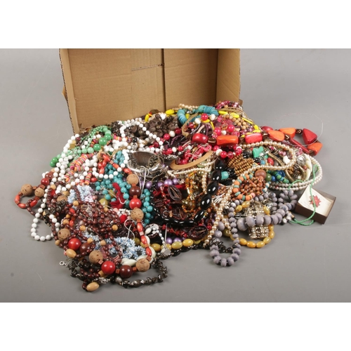 154 - A box of costume jewellery. Includes beads, bangle, earrings, ring etc.